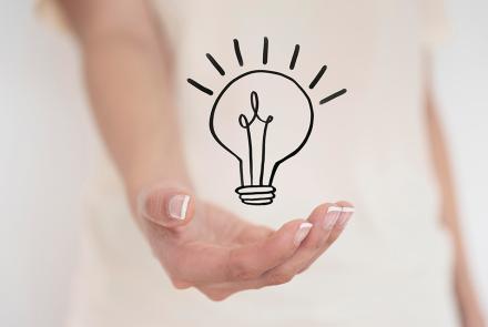 Open hand holding a simple line-drawn light bulb icon, symbolizing a new idea.